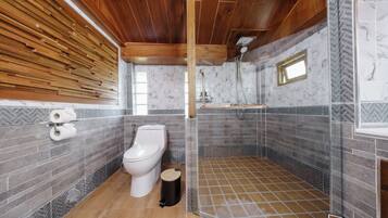 A modern bathroom with a wooden ceiling, a toilet, a shower enclosure, and a marble-tiled wall.