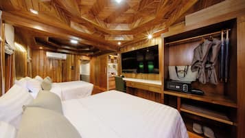 A wooden-themed room with two beds, a TV, and a wardrobe with hanging clothes.