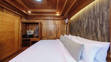 A wooden-paneled room with a bed, a coat rack, and a shelf with a radio.