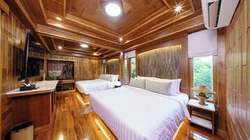 A wooden cabin with two beds, a TV, and a window with a view of greenery.