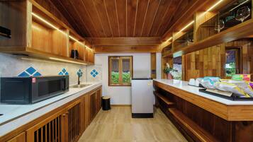 A kitchen with wooden cabinets, a microwave, a refrigerator, and a countertop with papers.