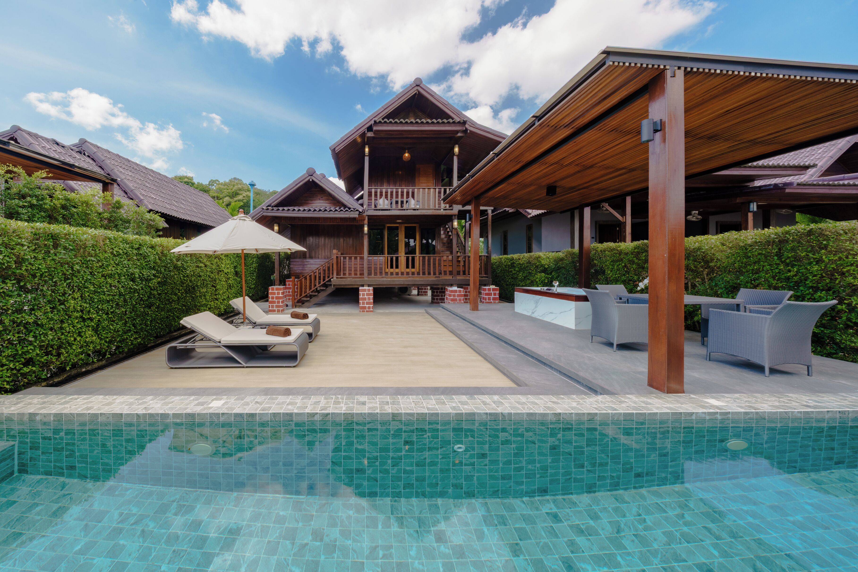 Un resort con piscina, sillones de descanso y mobiliario exterior.