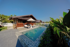 A swimming pool with lounge chairs and a wooden house in the background. - Calisto Valley I Luxury Pool Villa Krabi (Krabi)