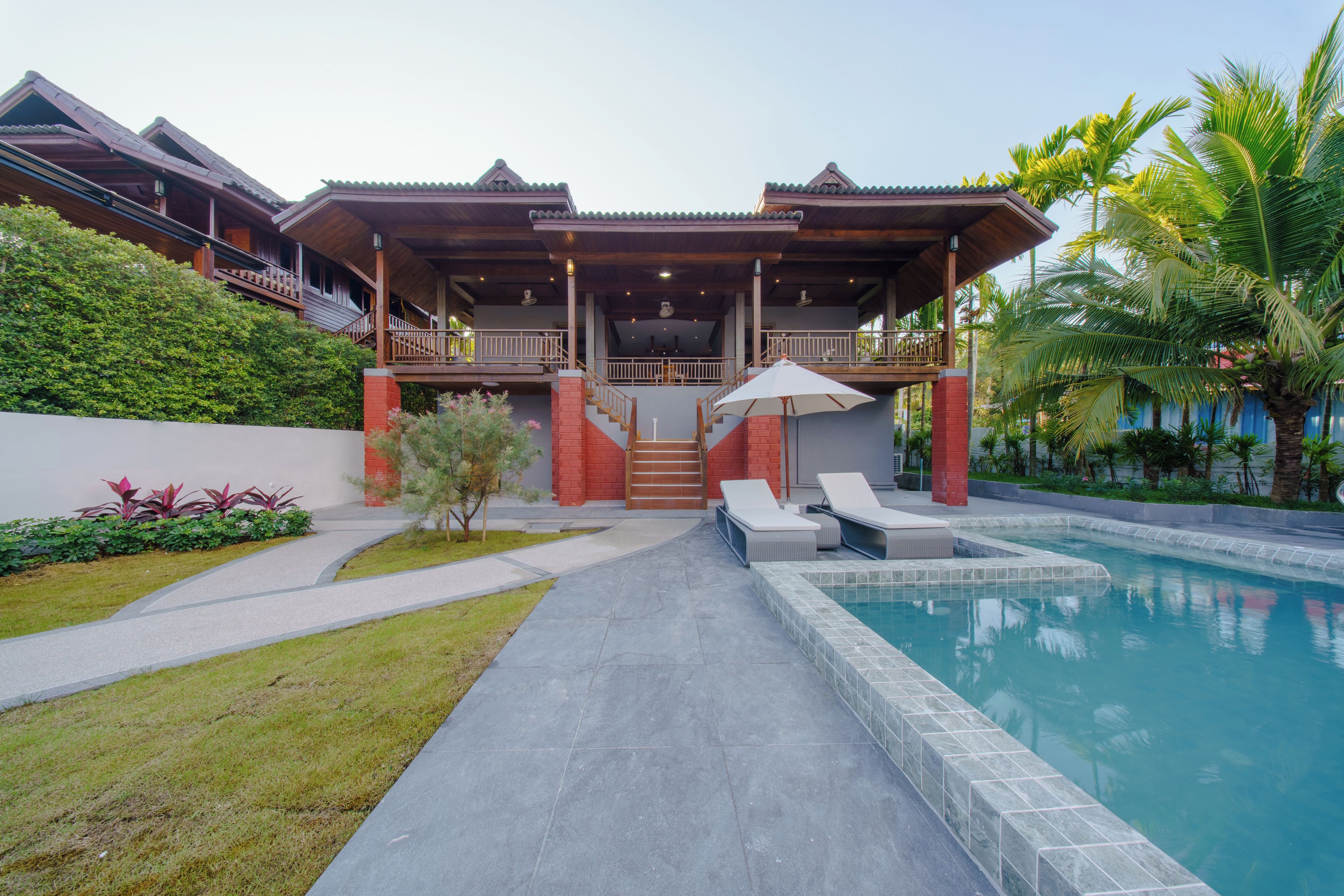 A resort with a swimming pool, outdoor seating, and a covered patio area.