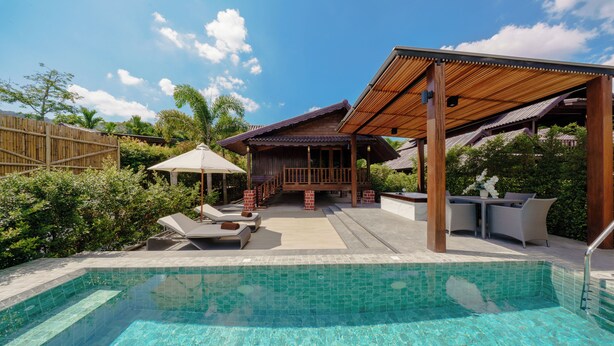 A swimming pool with a wooden deck and lounge chairs, surrounded by lush greenery and a clear blue sky. - Calisto Valley I Luxury Pool Villa Krabi (Krabi)