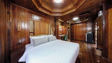 A wooden-paneled room with a bed, a small table, and a refrigerator.