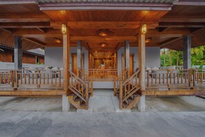 A wooden covered walkway with a central staircase leading to a covered area, surrounded by a white fence and greenery. - Calisto Valley I Luxury Pool Villa Krabi (Krabi)