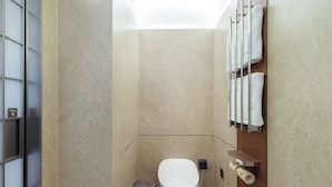 A modern bathroom with a toilet, a trash bin, a towel rack, and a glass partition. - Novotel Xiamen International Convention Center (Xiamen)