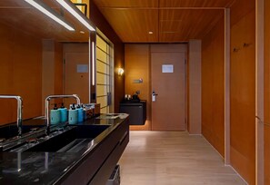 Eine moderne Küche mit schwarzem Arbeitsplatz, Spüle aus Edelstahl und blauen Wasserspendern. Es sind Holzschränke und ein eingebauter Backofen vorhanden.