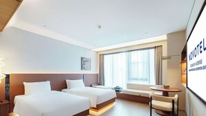 Ein Hotelzimmer mit zwei Betten, einem Schreibtisch und einem großen Fenster.