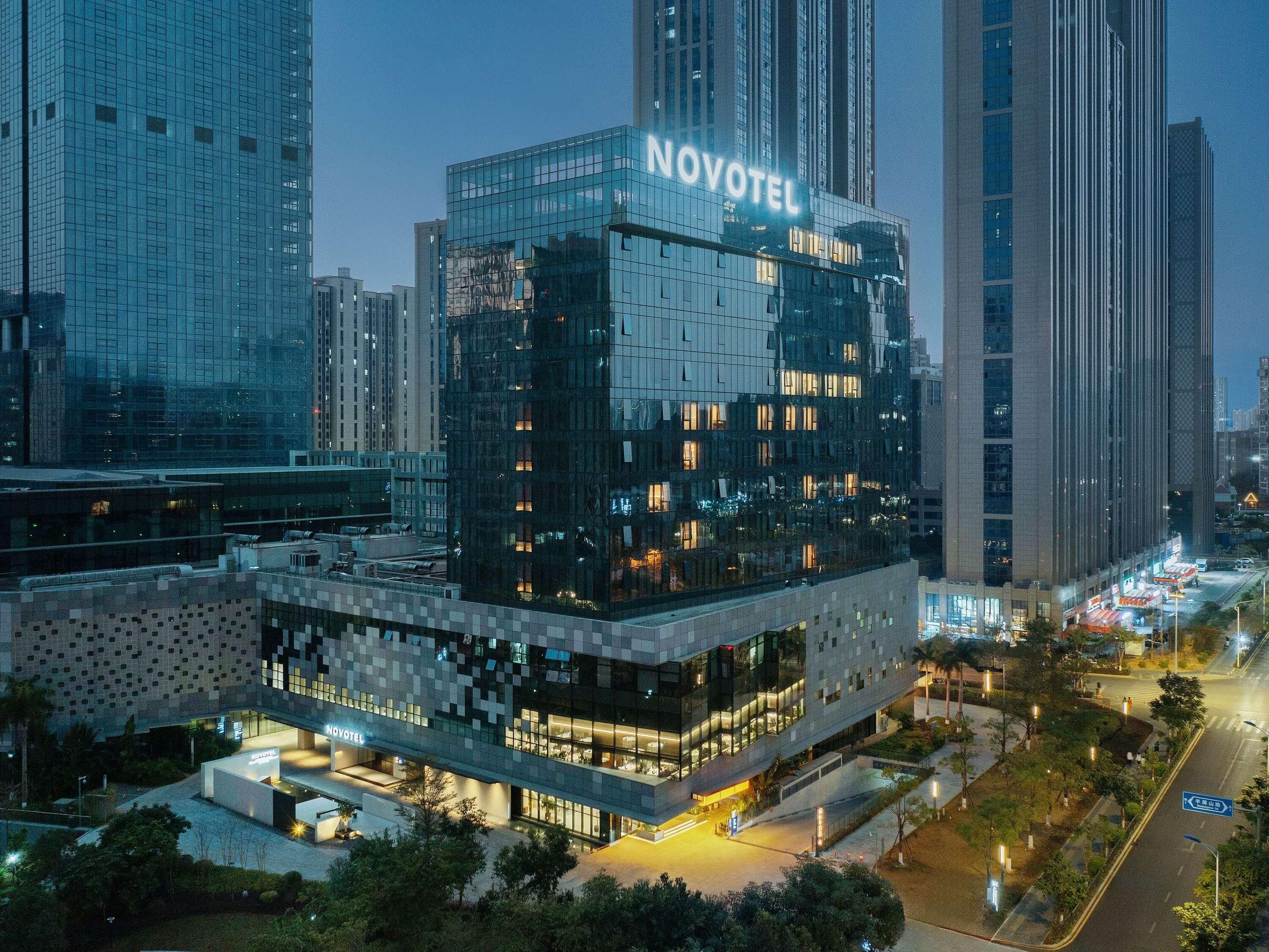 Un hotel moderno con fachada de vidrio y el nombre 'NOVOTEL' claramente visible.
