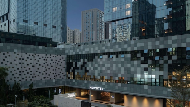 A modern hotel with a geometric facade, a well-lit entrance, and a landscaped outdoor area. - Novotel Xiamen International Convention Center (Xiamen)