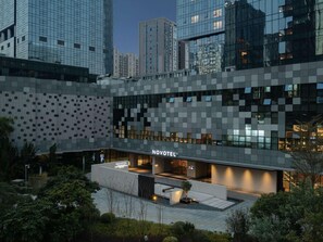 Een modern hotel met een geometrisch gevelontwerp, een goed verlichte ingang en een aangelegde buitenruimte.