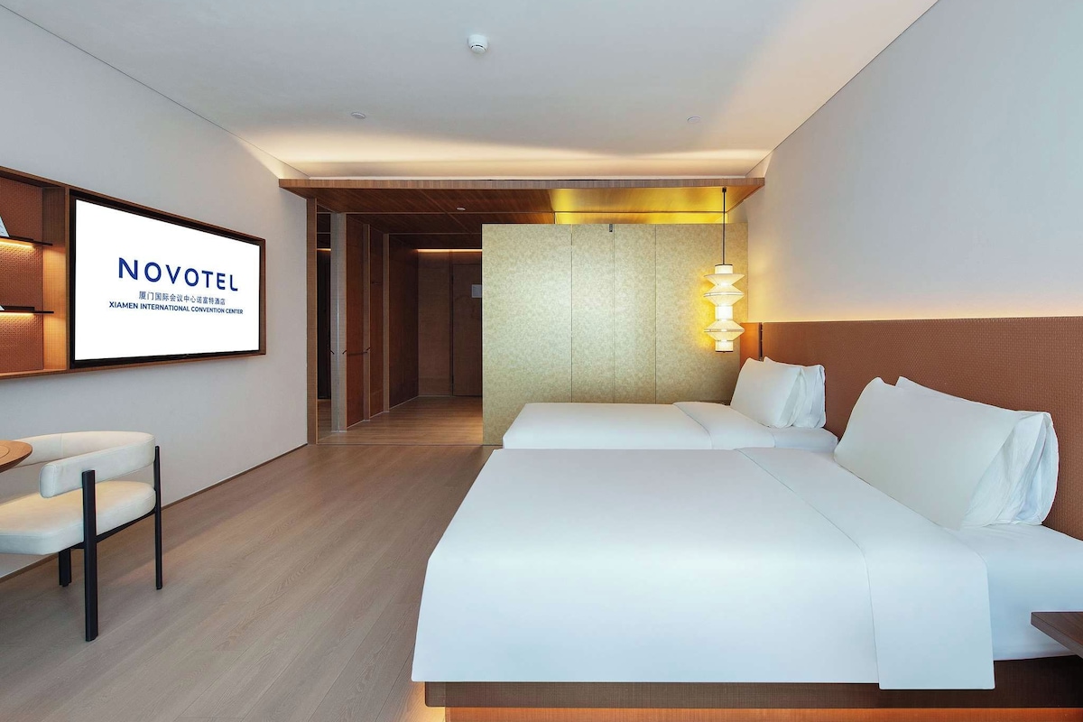 Ein Hotelzimmer mit einem großen Bett, einem Schreibtisch mit Stuhl und einem gerahmten Schild an der Wand.