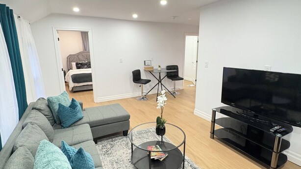 A modern living room with a grey sectional sofa, a glass coffee table, and a flat-screen TV.