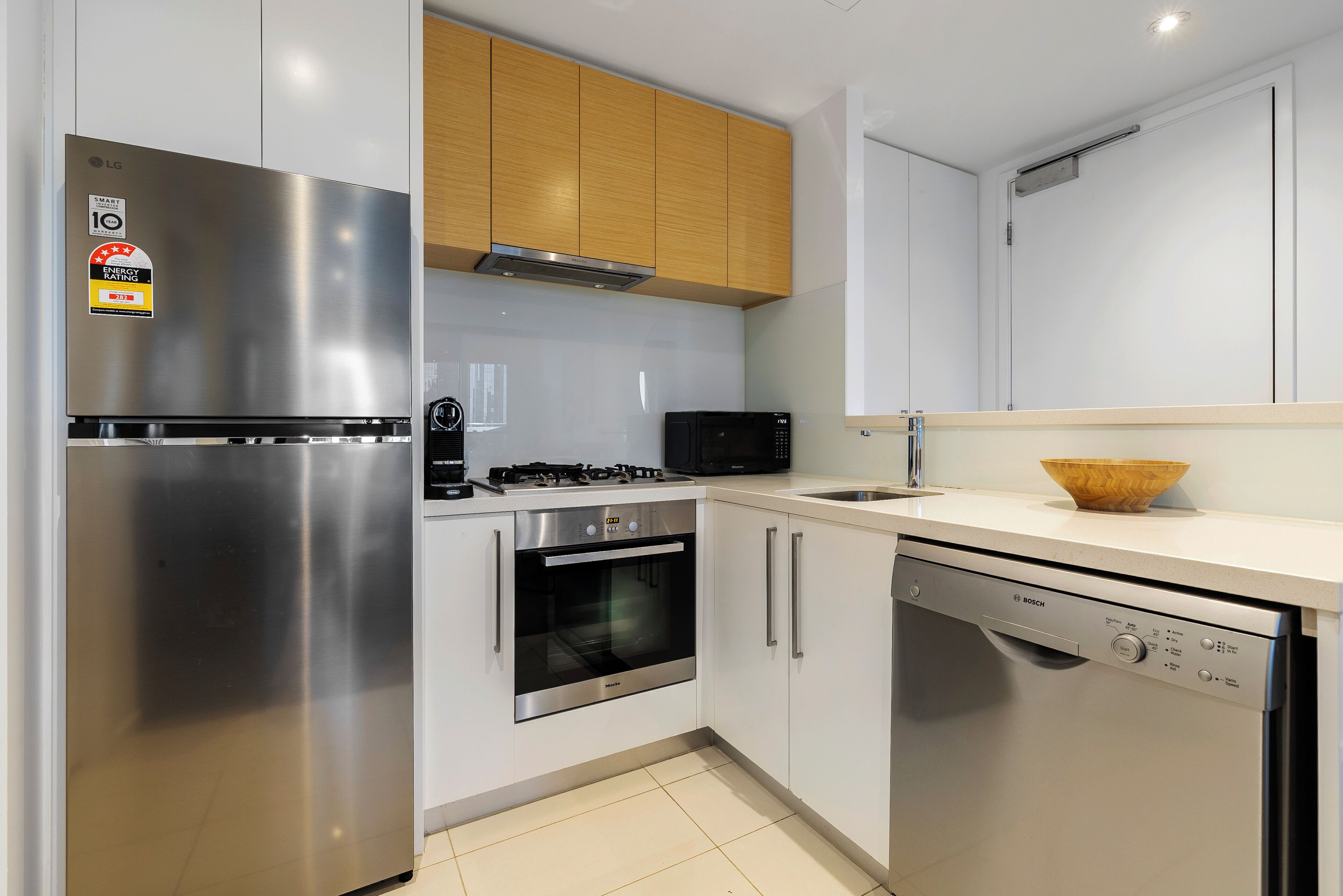 Eine moderne Küche mit einem Edelstahl-Kühlschrank, Backofen, Geschirrspüler von Bosch und einer Mikrowelle.