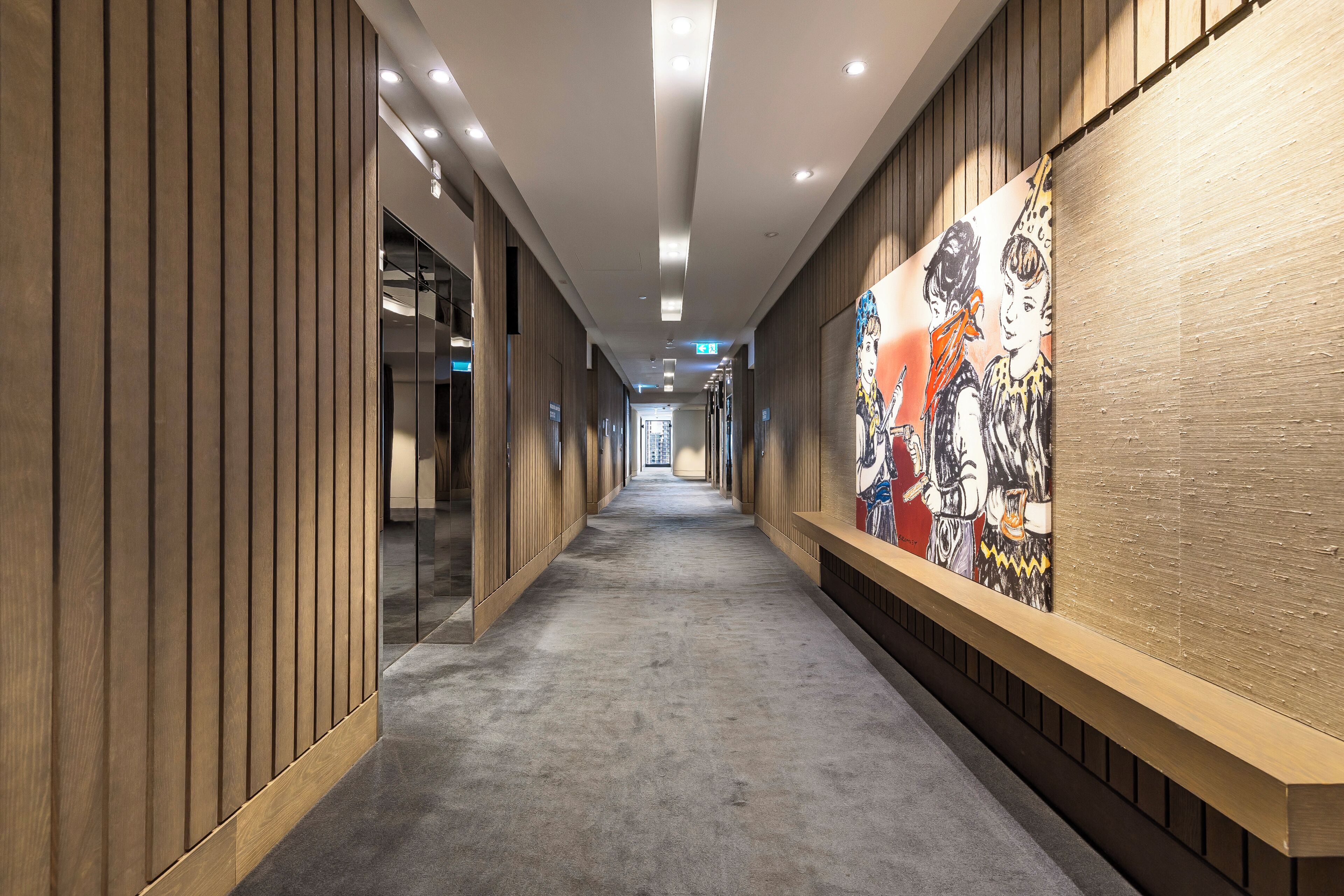 A hallway with wooden paneling, a carpeted floor, and a colorful mural on the right wall.