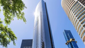A modern high-rise building with a curved facade, surrounded by other tall buildings and trees. - Southbank Stay in Prima Tower | Premium Facilities (Southbank)