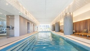 An indoor swimming pool with clear water, surrounded by modern architecture and a glass wall on one side. - Southbank Stay in Prima Tower | Premium Facilities (Southbank)