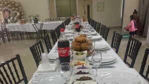 Una larga mesa de comedor dispuesta con platos, vasos y diversos platos, probablemente en un comedor de hotel.