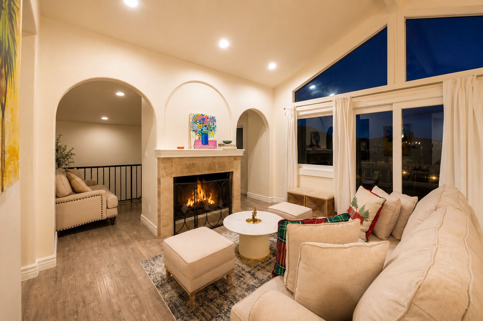 A living room with a fireplace, a sofa, a coffee table, and a view of the city at night.