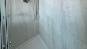 Une douche moderne dotée d’un pommeau de douche carré et d’un flexible de douche.