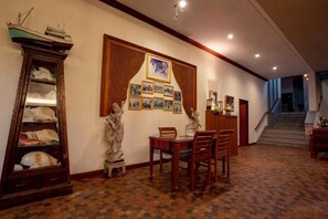 A hallway with a patterned carpet, a wooden cabinet, a dining table with chairs, and a staircase in the background. - Sailom Hotel Hua Hin (Hua Hin)