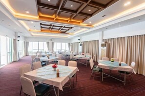 A hotel conference room with multiple tables, chairs, and a large window providing natural light. - Sailom Hotel Hua Hin (Hua Hin)