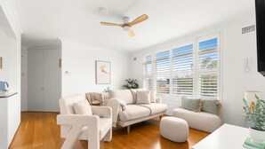 A modern living room with a beige sofa set, a white coffee table, and a ceiling fan. - Bright 2-bed Flat With Balcony in Vaucluse (Sydney)