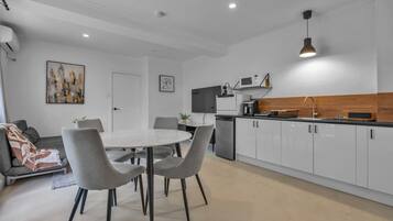 A modern kitchen with white cabinets, a round dining table, and grey chairs.
