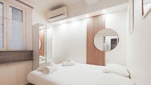 A modern bedroom with a bed, a large mirror, and an air conditioning unit.