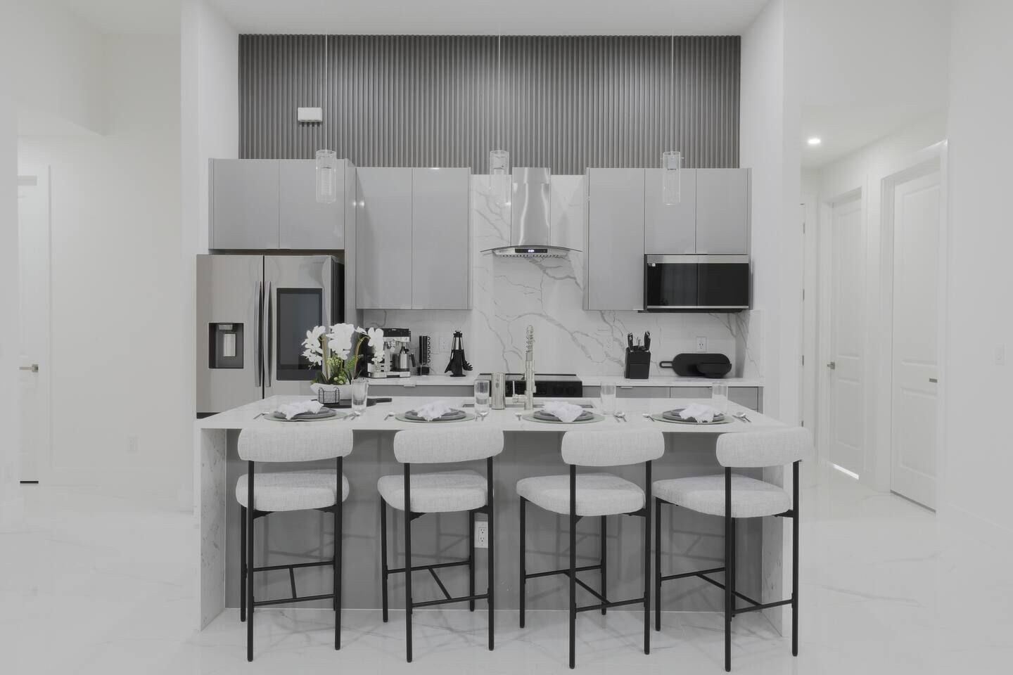 A modern kitchen with a central island, bar stools, and a built-in microwave.