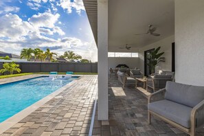 A swimming pool with lounge chairs and a patio area with seating. - Is This Cape`s Best Secret? | 4BR Midnight Pool (Cape Coral)
