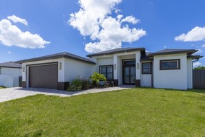 Een woonhuis met twee verdiepingen, een garage, een voortuin en een verzorgd gazon.