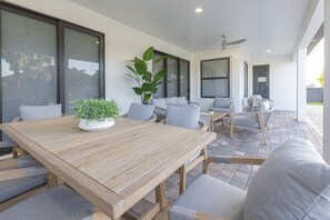 Een terras met een houten tafel, stoelen en een potplant.