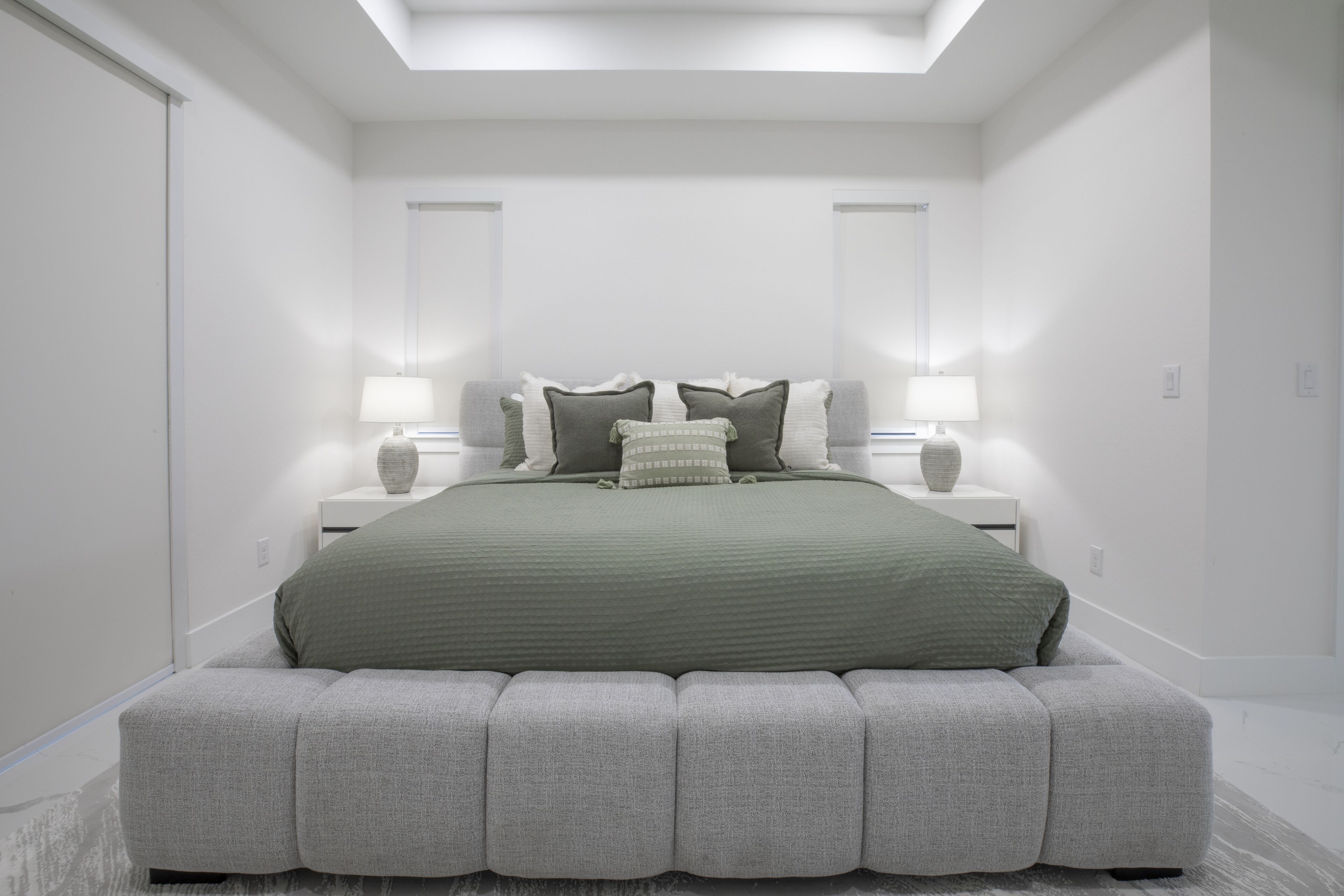 Ein modernes Schlafzimmer mit einem großen Bett, zwei Nachttischen und einem Oberlicht.
