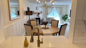 Une cuisine avec une table ronde, des chaises, un évier et un lustre.