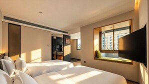 A hotel room with two beds, a TV, a window with a view, and a built-in desk. - DOTTEL HOTEL (Shantou)