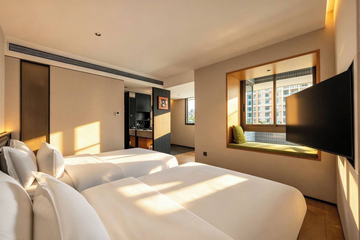 A hotel room with two beds, a TV, a window with a view, and a built-in desk.