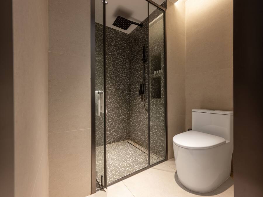 A bathroom with a glass-enclosed shower, a toilet, and tiled walls.