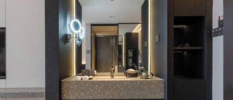 Un baño moderno con encimera de granito, lavamanos dobles y un espejo grande con iluminación integrada.