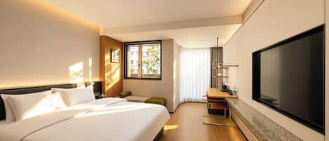 A modern hotel room with a large bed, a flat-screen TV, a desk, and a window with blinds.