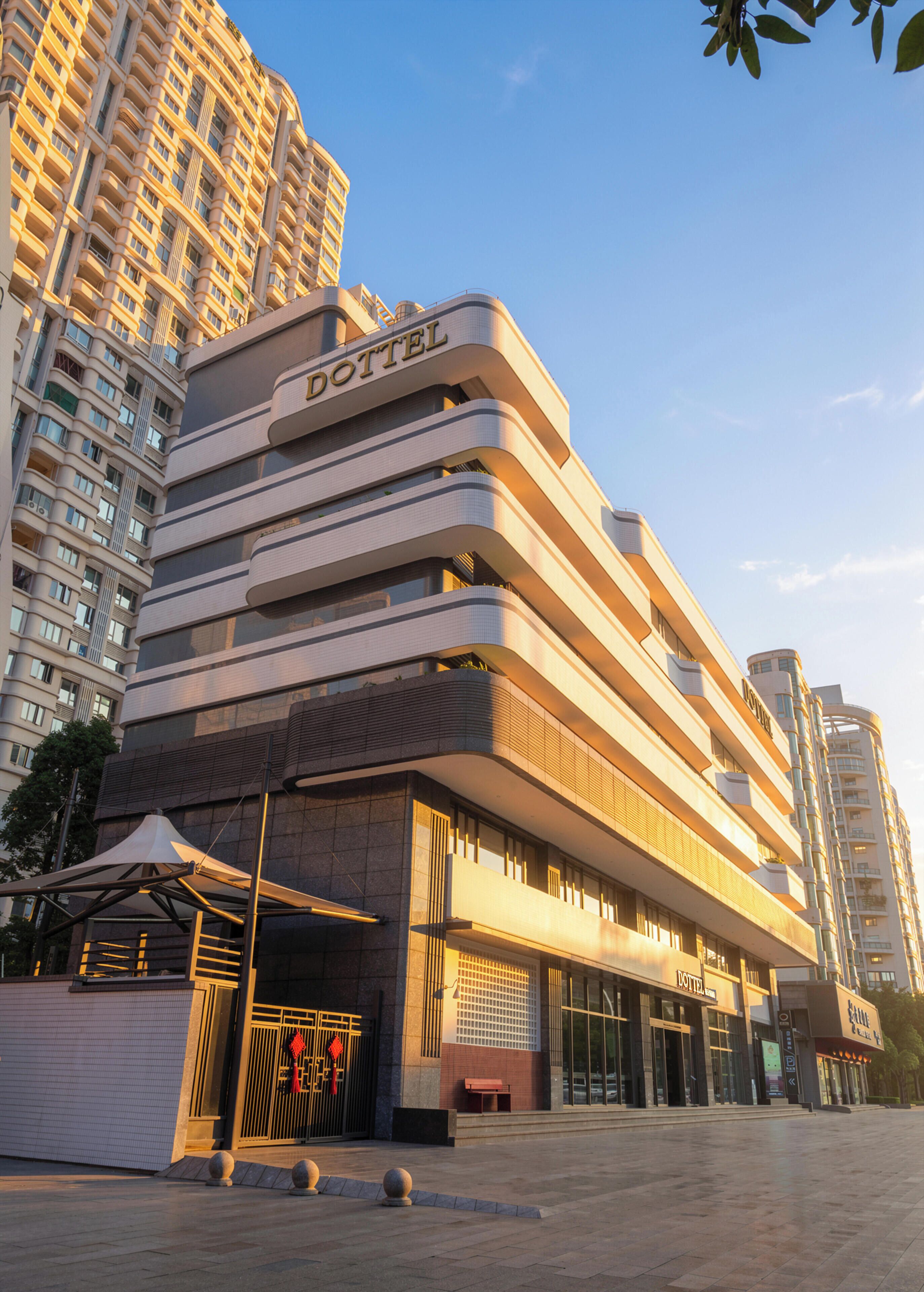 A modern hotel with a prominent 'HOTEL' sign, multiple balconies, and a spacious entrance area.