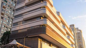 A modern hotel with a prominent 'HOTEL' sign, multiple balconies, and a spacious entrance area.