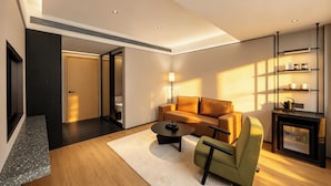 A modern living room with a sofa, coffee table, and armchair, a fireplace, and a built-in shelf with items. - DOTTEL HOTEL (Shantou)