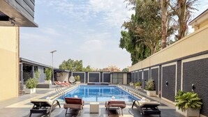 A swimming pool with lounge chairs and potted plants.