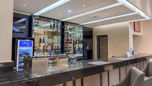 A bar area with a glass partition, shelves of liquor bottles, and a counter with a menu display.