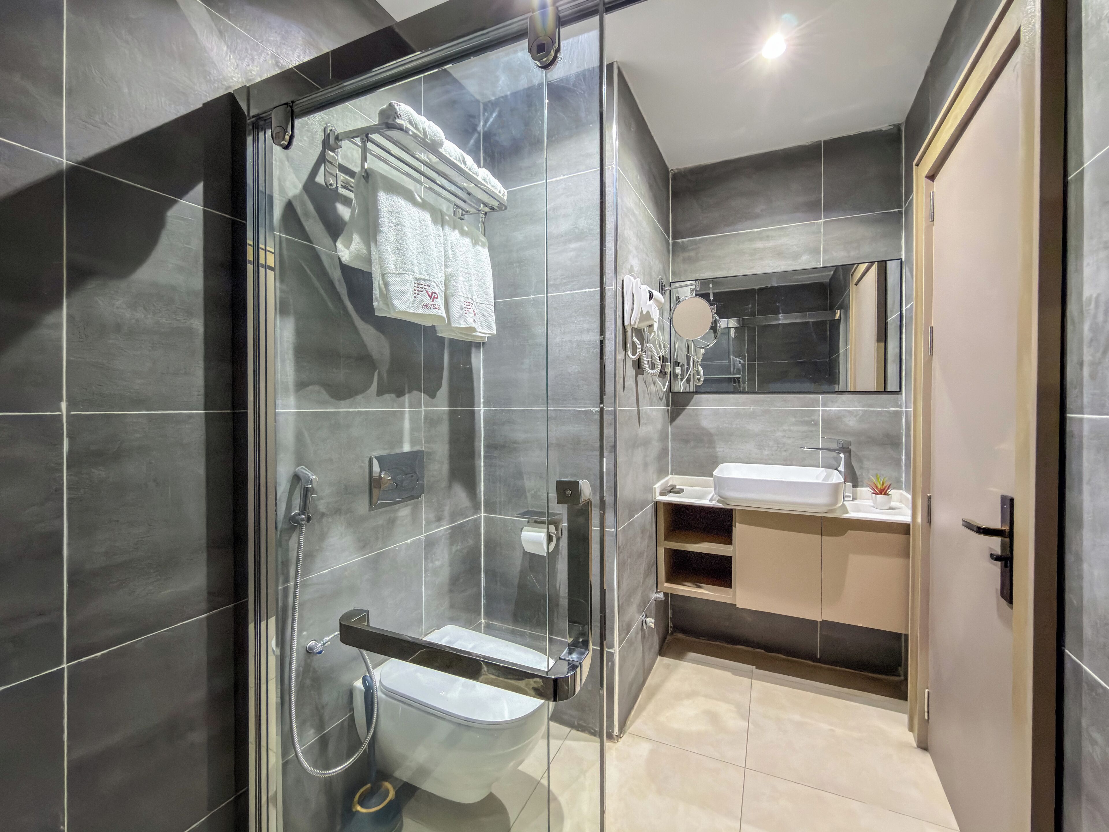 Une salle de bain moderne avec une douche à parois de verre, des toilettes, un lavabo et un miroir.