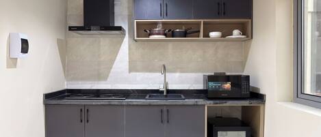 A compact kitchen with dark cabinets, a built-in microwave, and a small refrigerator.