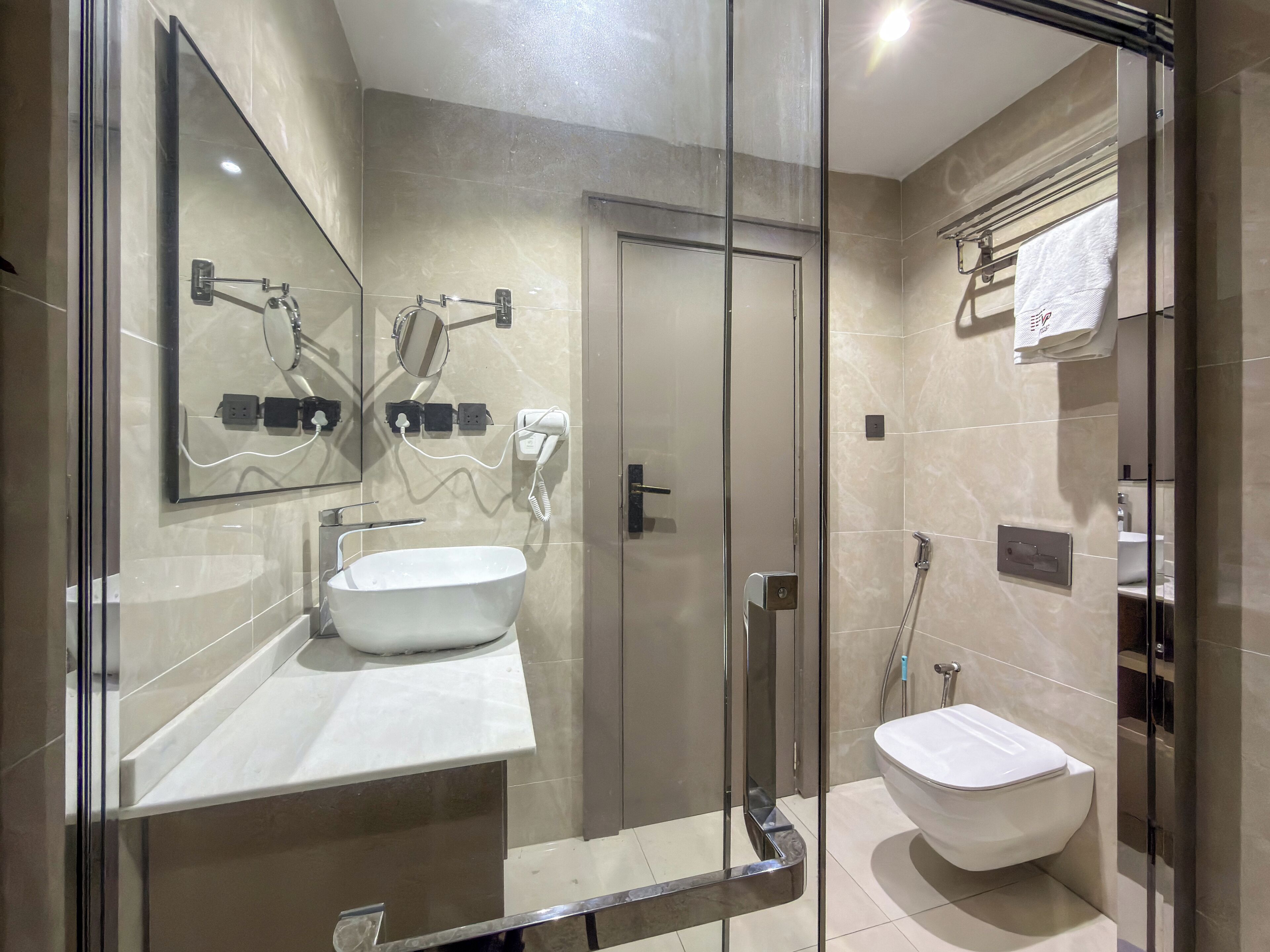 Un baño moderno con cabina de ducha de vidrio, un lavamanos blanco y un inodoro.